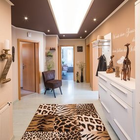Afrikanisch inspirierter Flur mit Tiermusterteppich, Dekofiguren und Wandkunst.