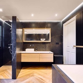 Modernes Badezimmer mit dunklen Marmorfliesen, Holzwaschtisch und bodengleicher Dusche.