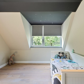 Modernes Kinderzimmer mit Dachschräge, Holzboden, Kinderbett und Plüschspielzeugen.