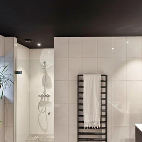 Modernes Badezimmer mit bodengleicher Dusche, weißen Fliesen und schwarzem Handtuchheizkörper.